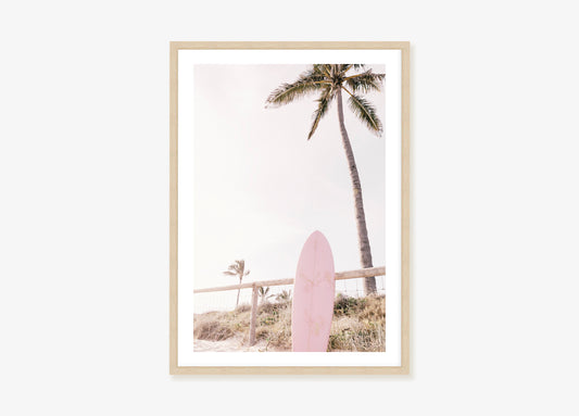 a pink surfboard sitting in front of a palm tree